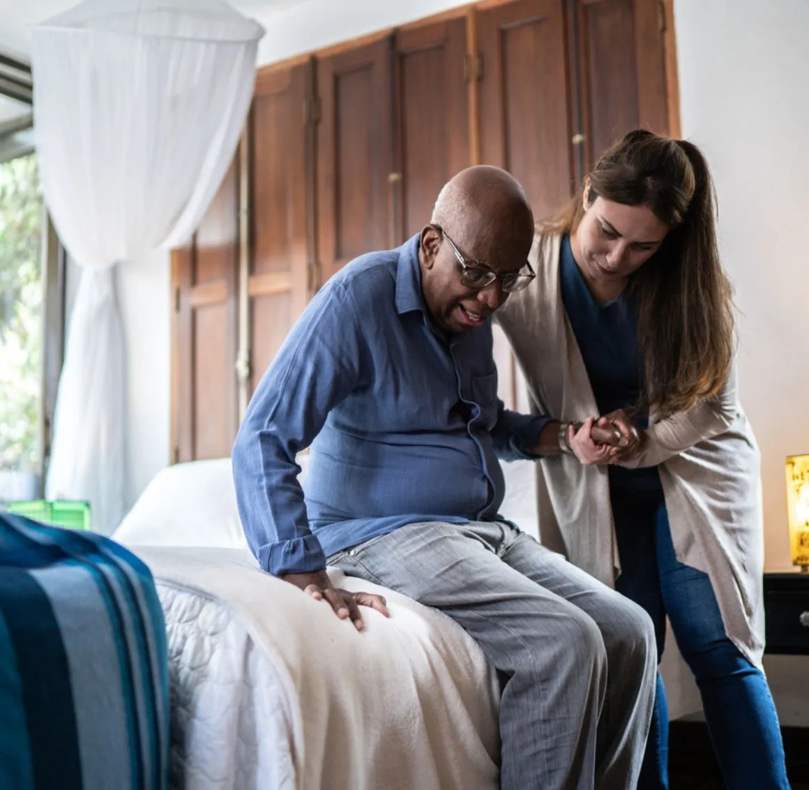 Companion Care in Saratoga caregiver helping an older adult safely get out of bed with compassionate assistance.